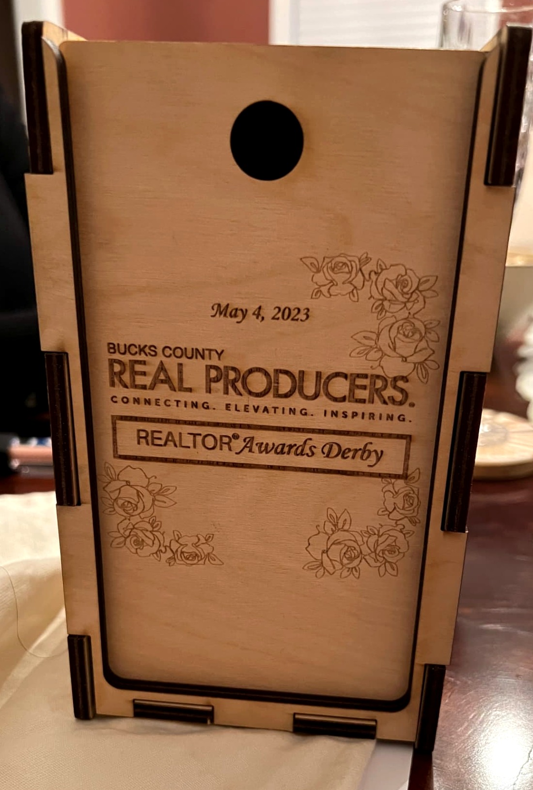 A handcrafted Baltic birch presentation box engraved with the REALTORS® Awards Derby crest, photographed on ivory stone