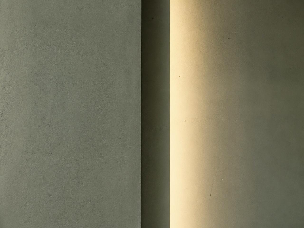 a minimal interior detail with an ivory plaster wall, sage textile and soft directional daylight